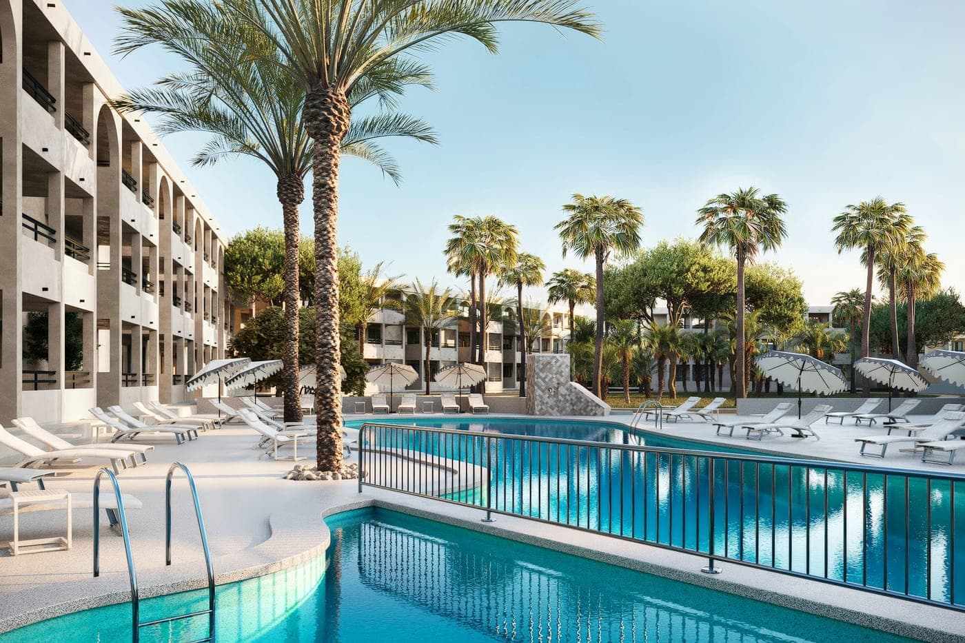 La piscina principal con tumbonas y sombrillas, rodeada de palmeras y de los edificios de apartamentos